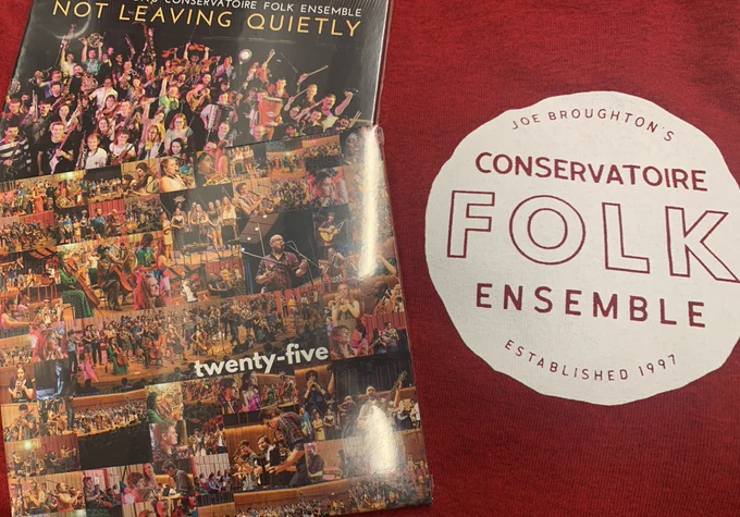 A photo of part of a red tshirt with a Conservatoire Folk Ensemble logo on it. There are two Conservatoire Folk Ensemble cds.