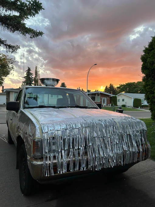 Photo of a car decked out in silver with a silver bowl on top and Edmonton Oilers flags in the windows.