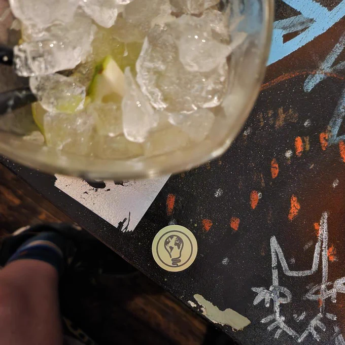And EWB sticker on a bar table which is covered in graffiti and stickers
