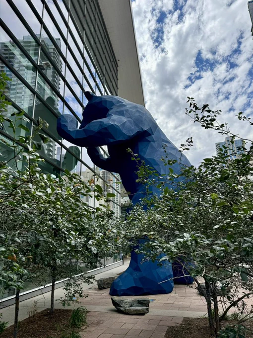 A large blue bear peers into a convention center
