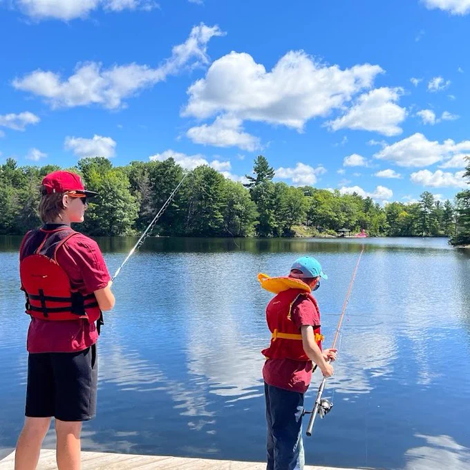 Two children wearing PFDs and fishing off a dock