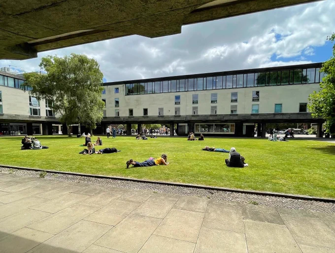 People relax on the lawn outside the Raised Faculty Building