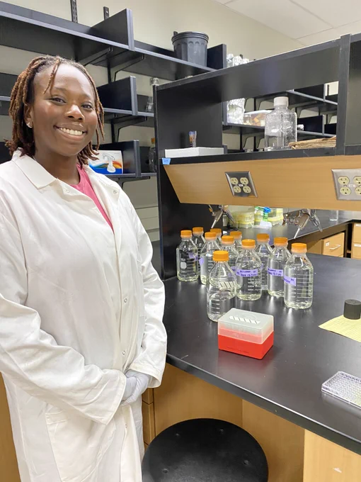 Ijeoma Nwafor, undergrad research assistant, poses in a long white lab coat.