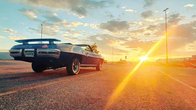 An American muscle car convertible faces the sunset inspiring action and forward movement. 