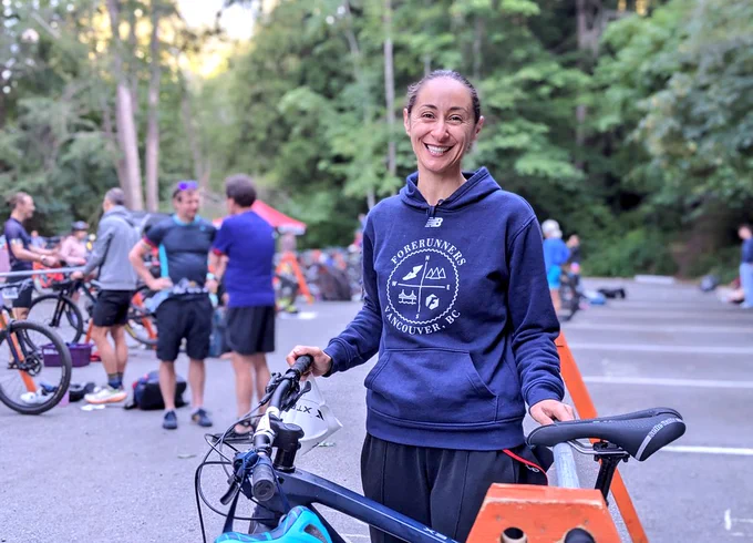 A racer poses with her bicycle in the transition zone. Big smile. 
