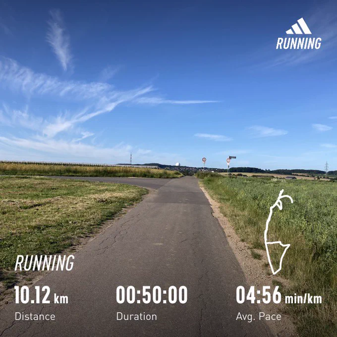 Road running through field, clear skies above; running stats superimposed (10:12km, 50mins)