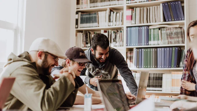 A group of four people laughing and enjoying their time in the library. 
