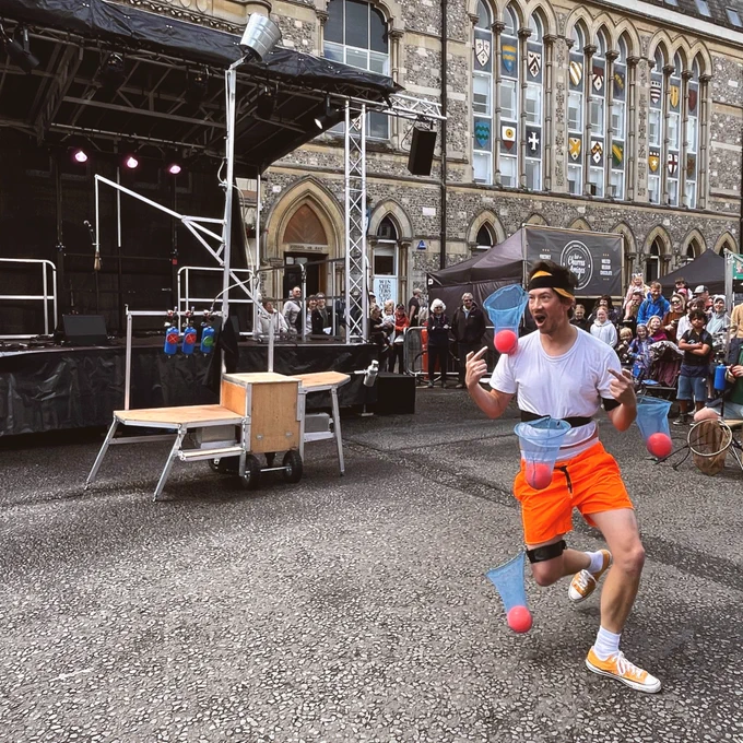 A man performs in front of a crowd in a street.