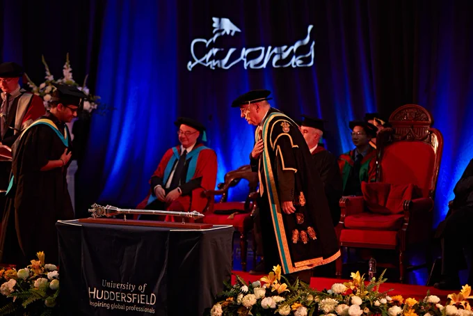 Graduate and University staff taking a bow as graduates walks stage