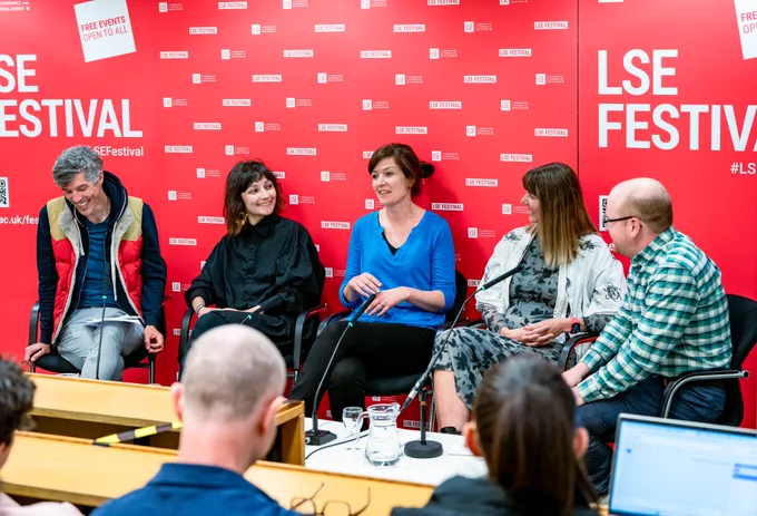 Four people sitting on a panel in front of a red LSE banner.