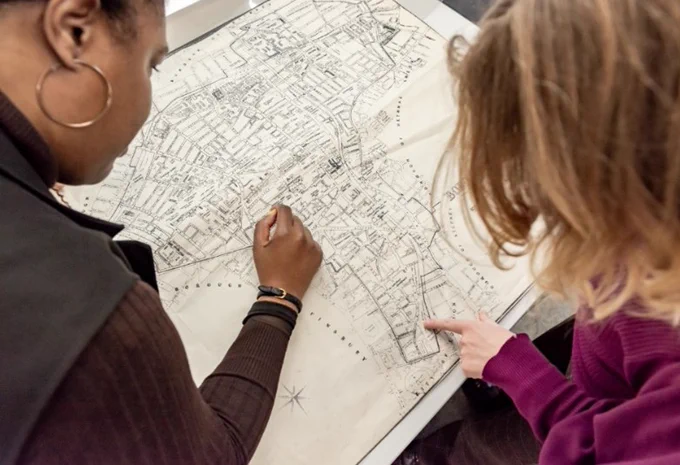 Birds-eye view of two people as they look at a detailed street map.