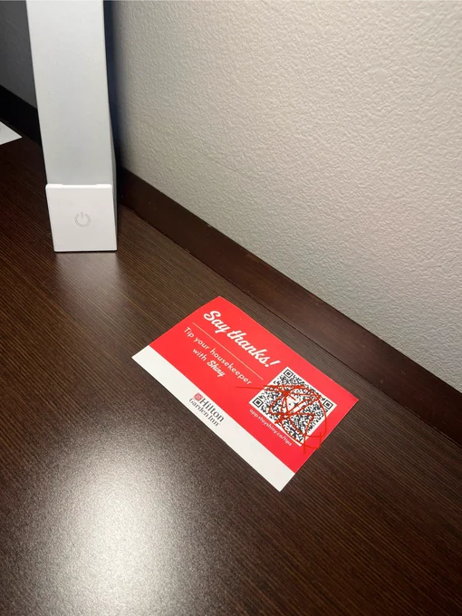 A business card with a QR code and instructions for tipping the housekeeping staff