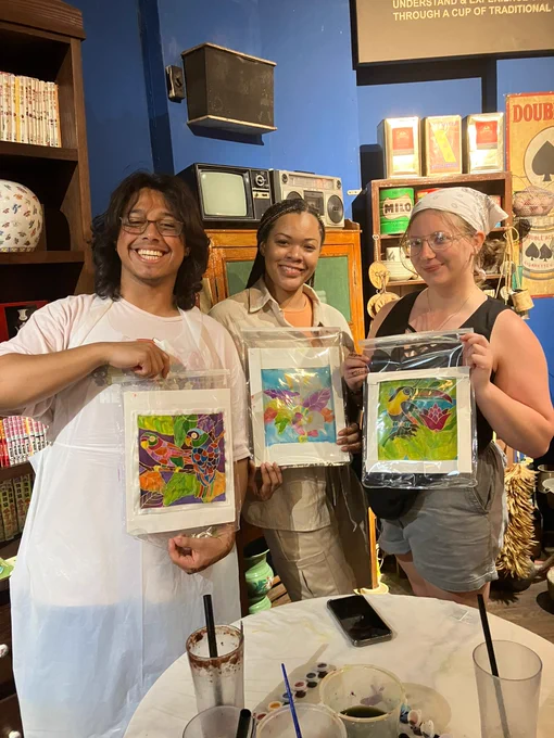 Students hold up art pieces