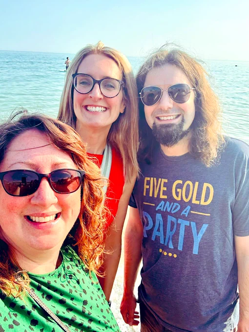 Photo of Sam, Anna and Mark on Brighton Beach smiling at the camera in the sunshine