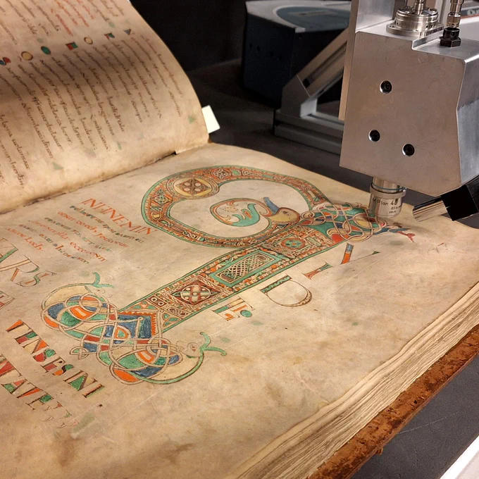 A colourful manuscript in Latin open under  ramen spectroscopy equipment 