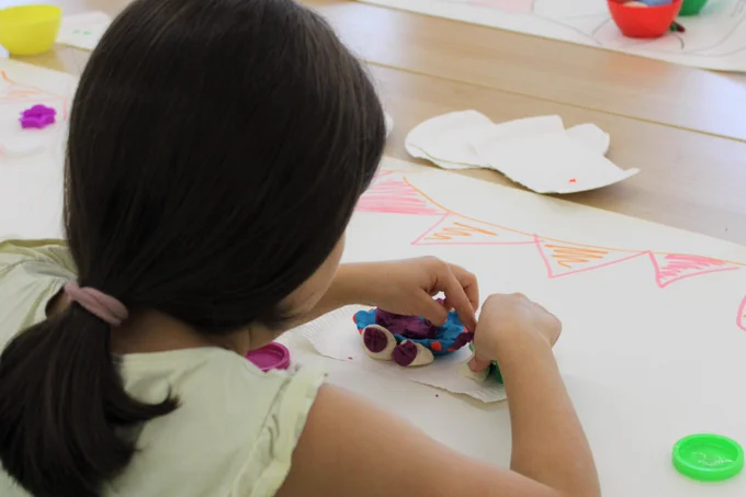 A child making a colourful festival float out of modelling clay 