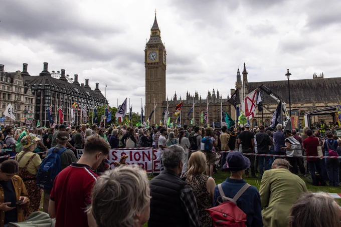 A large rally takes place in Parliament Square. Westminster Clock Tower (Big Ben) is in the background