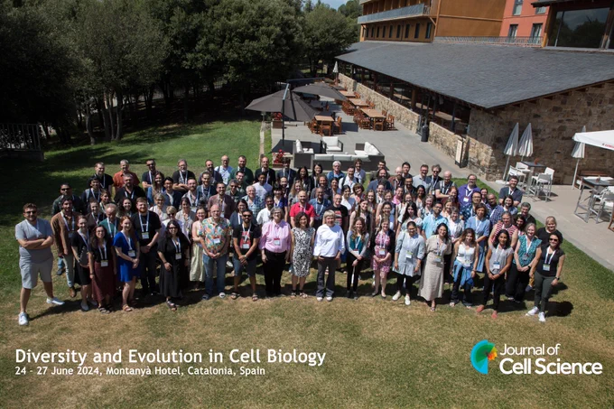 Group photo from #JCSevocellbio. The image shows a large group of people looking up at a camera. The text below the people is: Diversity and Evolution in Cell Biology 
24-27 June 2024, Montanya Hotel, Catalonia, Spain. The logo of Journal of Cell Science is in the bottom right of the image.