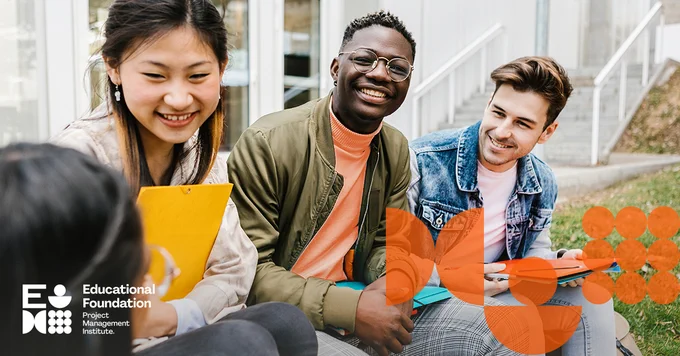 Three high-school aged students sitting together outside a school smiling and chatting