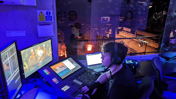A student sits at a lighting desk in the control box of the Chroma-Q Theatre