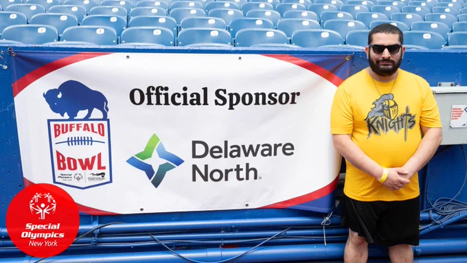 A competitor at the Buffalo Bowl stands beside a sponsor banner for Delaware North.