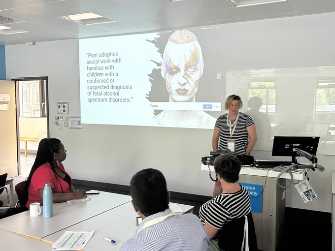 Becky stood in a teaching room, in front of PowerPoint presentation.