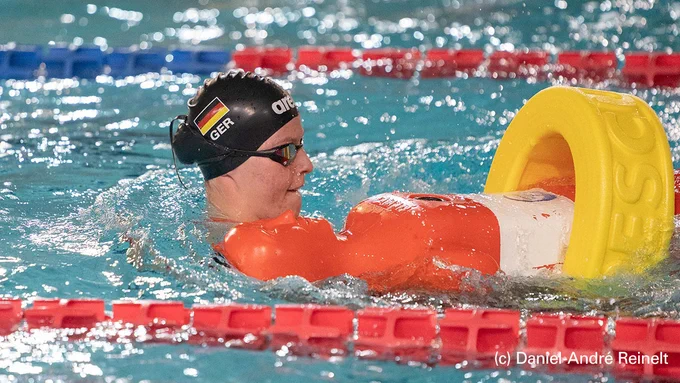 Eine Rettungssportlerin schleppt im Schwimmbecken eine Puppe mit einem Gurtretter ab.