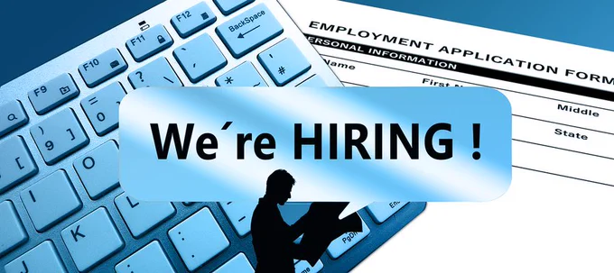 We're hiring! A keyboard with a job application form displayed on the screen. A person looking at a newspaper.