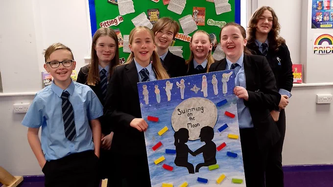 Students happily display their Spellbinding poster.