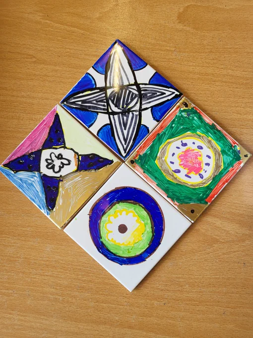 Plain white ceramic tiles decorated by children using Sharpies.  The patterns are bases on medieval tiles found in Malvern Priory.