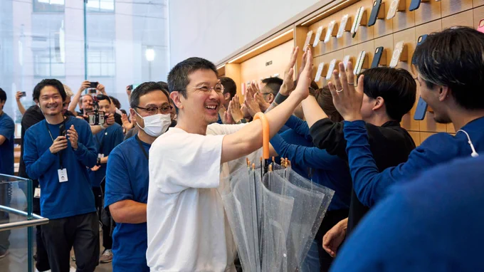 A customer high-fiving Apple retail team members as he walks into the store