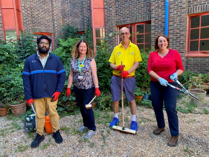 A group of people with gardening tools in a hospital courtyard