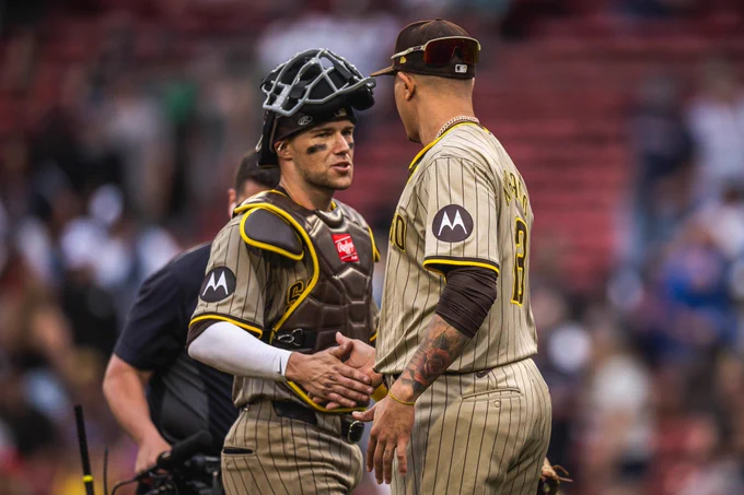 Photo of Brett Sullivan and Manny Machado giving each other a high five after today's win in Boston. Both are wearing the Padres sand road pinstripes uniform.