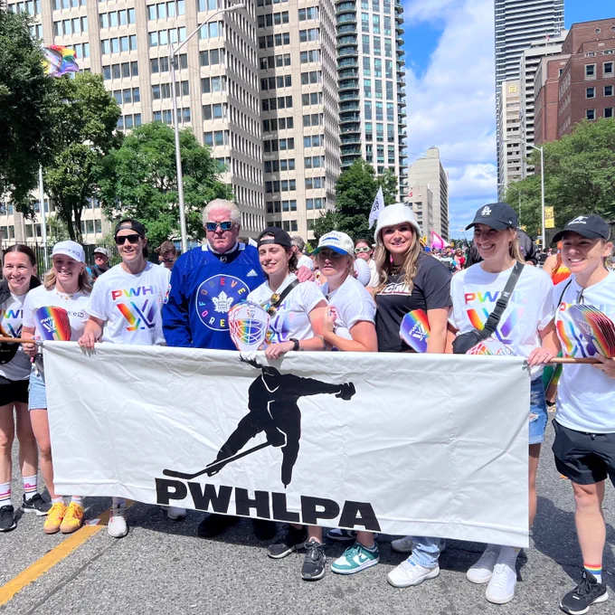 Members of the PWHLPA wearing Pride PWHL t-shirts, posing with a PWHLPA banner during the Toronto Pride Parade