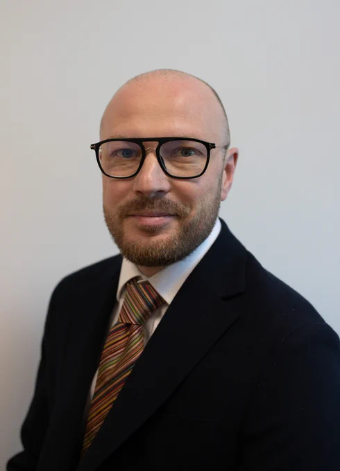 Chief medical officer Gareth thomas wearing glasses smiling at camera with shirt and tie on