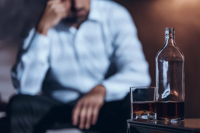 Man with bottle of drink and glass