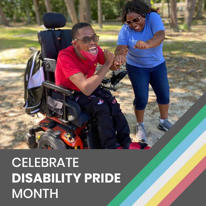A man in a motorized wheelchair outside with another person standing next to him. They are cheering and giving a fist bump to each other. On the bottom right is the Disability Pride rainbow colors and on the left is text that says, “Celebrate Disability Pride Month.”