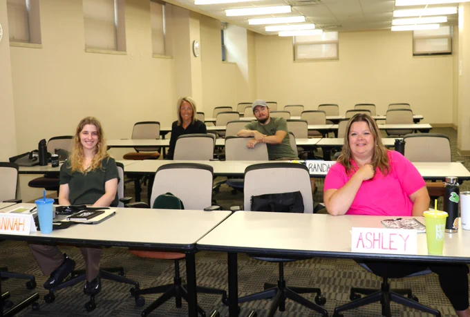 Four new hires sitting at tables for orientation