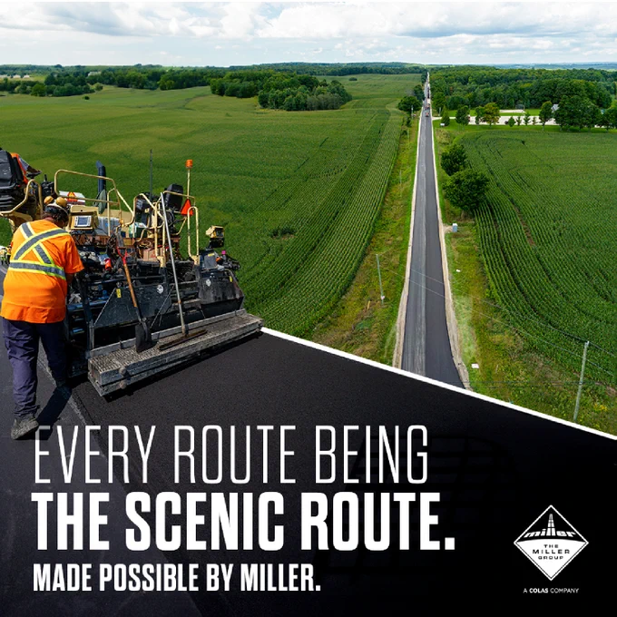 The image shows an aerial view of a road and a lush green rural landscape. A group of workers and a large paving machine are actively laying down new asphalt on the road. Text overlay reads, "Every route being the scenic route. Made possible by Miller." 