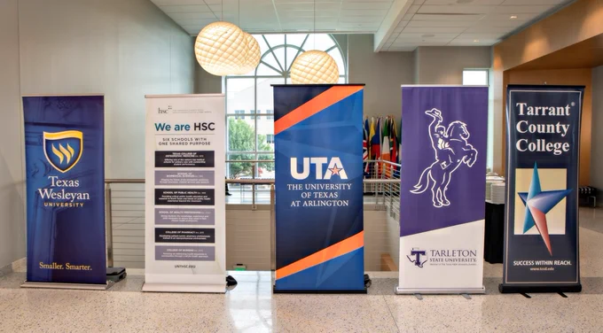 A row of university banners which include Texas Wesleyan, UNT HSC, UTA, TSU Fort Worth, and TCC.