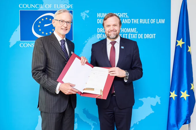 Council of Europe Deputy Secretary General Bjørn Berge and Ambassador Jean-Cédric Janssens de Bisthoven hold together the instrument of ratification of the Council of Europe Convention on the Manipulation of Sports Competitions (CETS No. 215) signed by Belgium