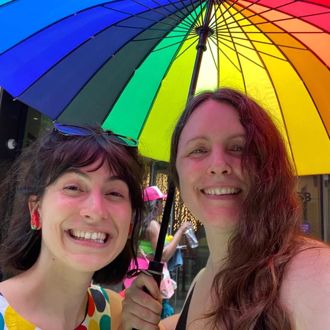 Dr.Betty Kolod, left, and Morgan Moore, right, smiling with rainbow umbrella behind them