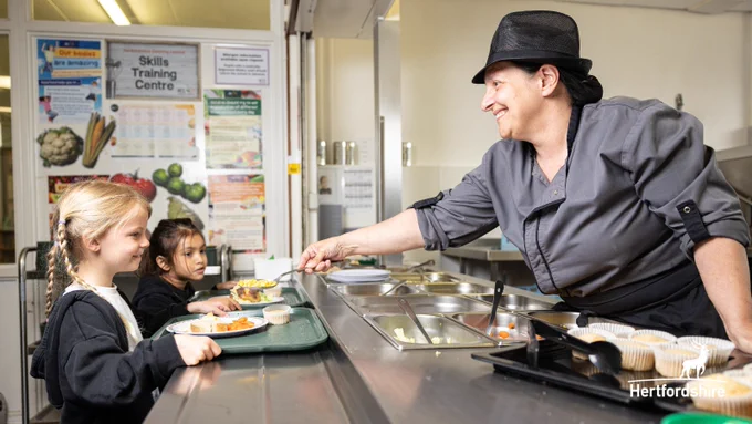 "Person handing two children a plate of food"

