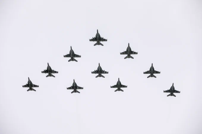 Multiple planes fly in triangular formation in the sky.