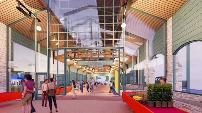 Architectural rendering on the new indoor market space, with modern glass and wood details. People are casually walking about in various directions, some are standing and looking at stalls. The central walkway is lined with hanging lights and banners that read "LOCAL MARKET" in bold letters.