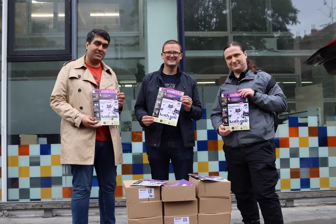 Photo from left to right: Mohsen, Marc Reichelt, Matthias Geisler - all standing and holding the fun code () Magazine in their hands. 
In front of their feet are multiple boxes.