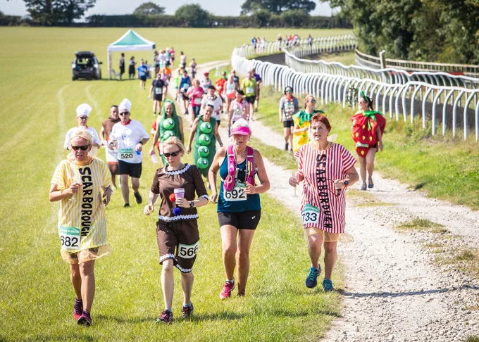 Runners on the gallops in Malton, a section of the Malton 10k course, dressed as chocolate and sticks of rock from local coastal destination, Scarborough. 