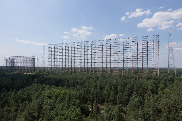 a long range shot of the Russian Duga radar station near Chernobyl, a series of giant interconnected towers like a net for electromagnetic signals, in the background a smaller version can be seen