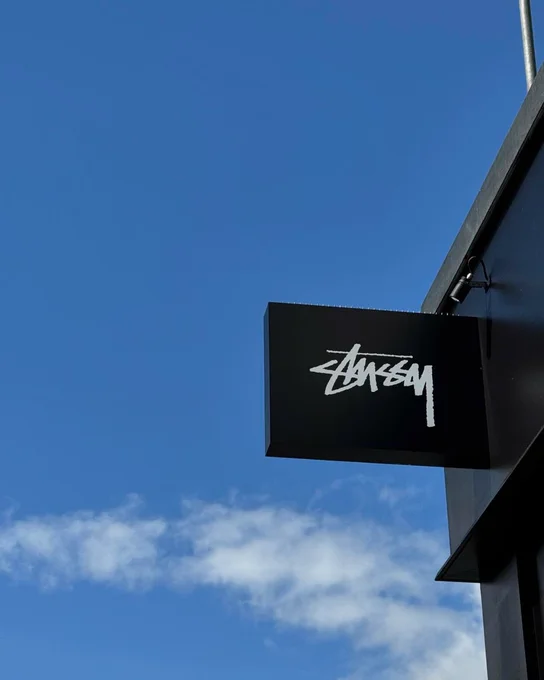 Black sign that says Stussy in front of a blue sky in Margate