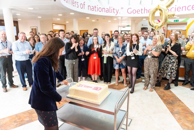 CEO of STEM Learning, Severine, cutting cake in front of staff.